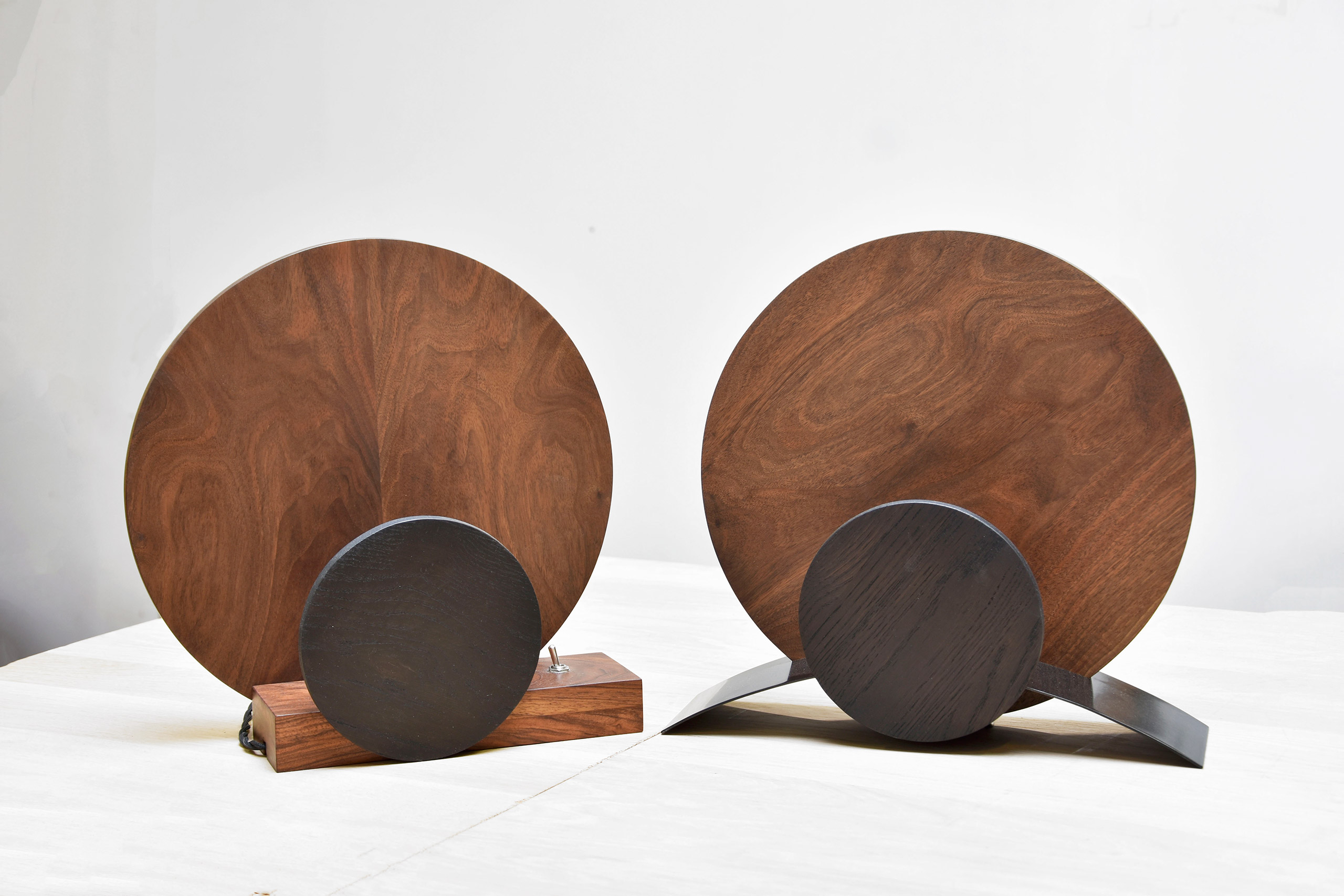 deux lampes ronde en bois de noyer et metal pose sur un meuble