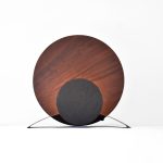 lampe ronde en bois fonce et metal pose dans un fond blanc