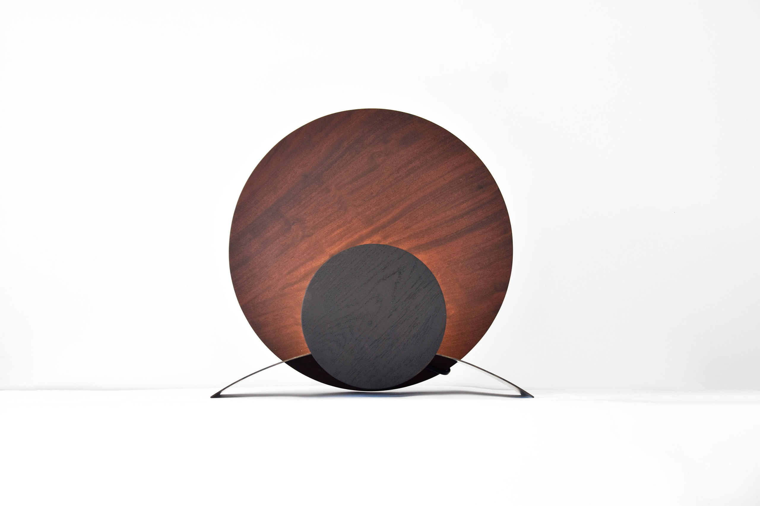 lampe ronde en bois fonce et metal pose dans un fond blanc